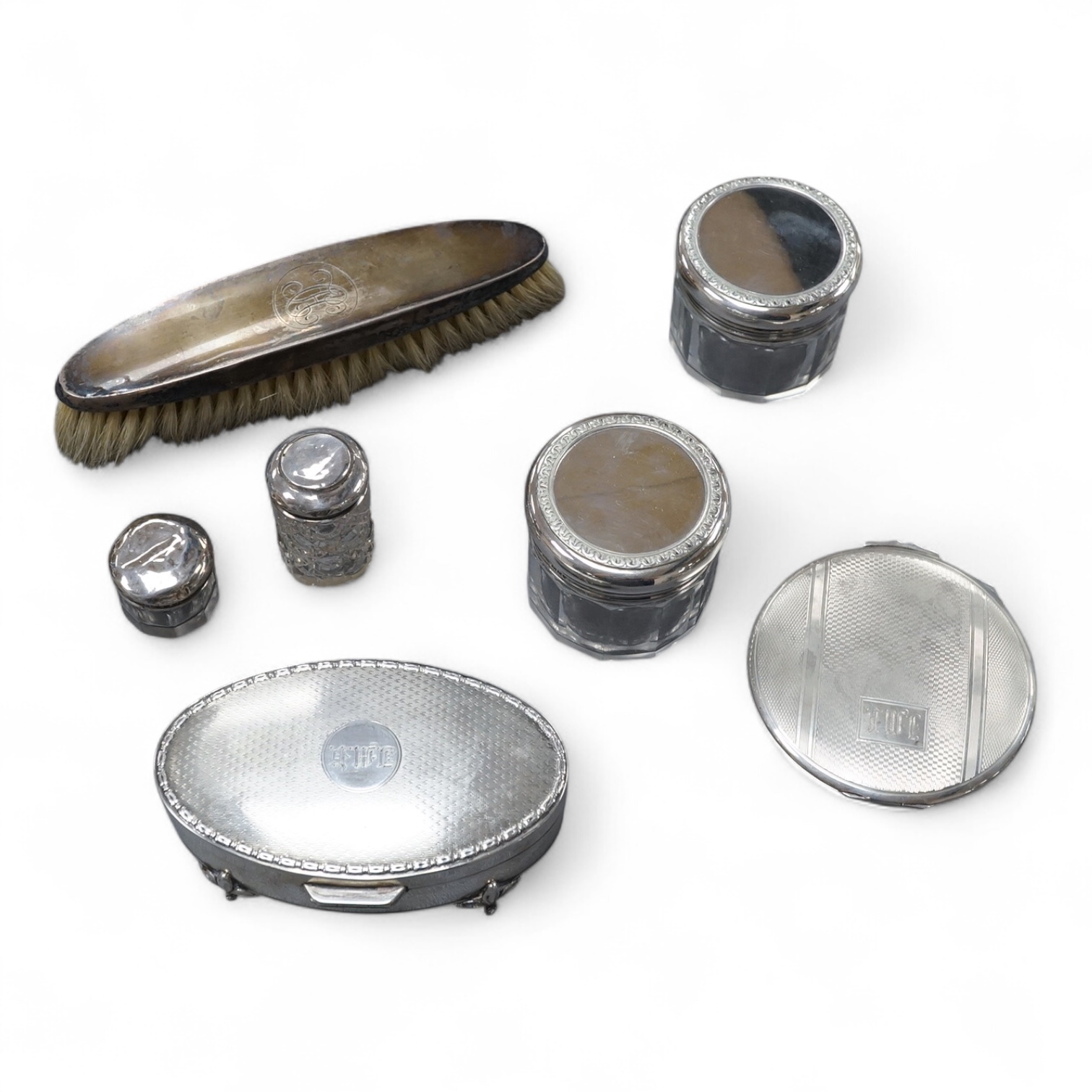A George V oval silver trinket box, Adie Bros. Birmingham, 1922, 10.8cm, together with a silver compact, four assorted silver mounted toilet jars and a silver mounted hair brush.